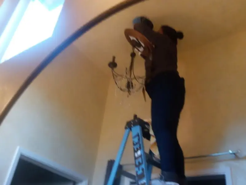 Electrician installing a chandelier in a San Jose residence